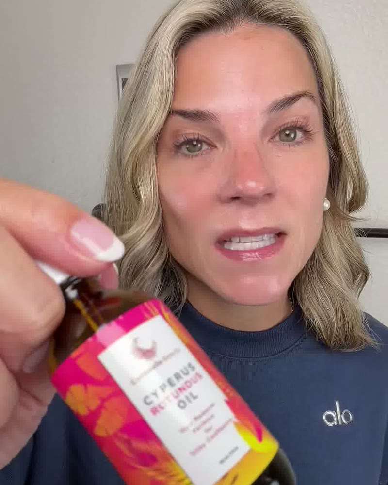 Creator Jenn Suggs holding the Caramela Cyperus Rotundus Oil bottle toward the camera