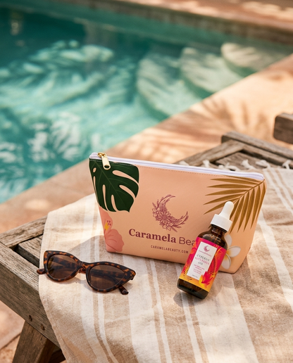 Caramela tropical pouch and Cyperus oil bottle on a sun lounger towel by the pool