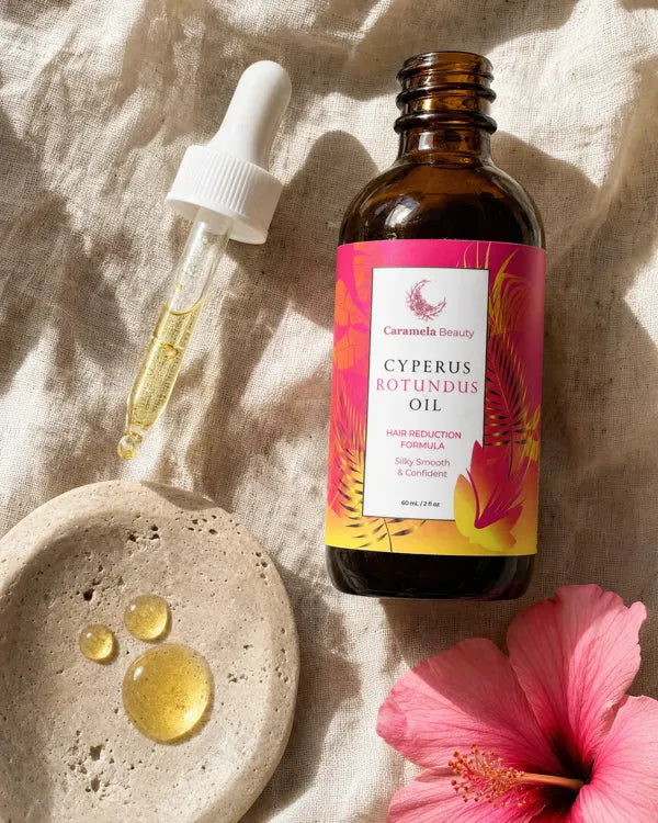 Caramela oil bottle on linen with oil drops and a pink hibiscus
